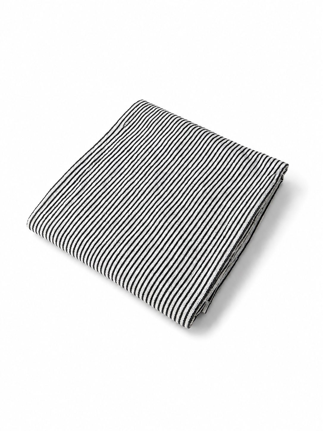 Folded black and white striped beach towel viewed at an angle on a white background.